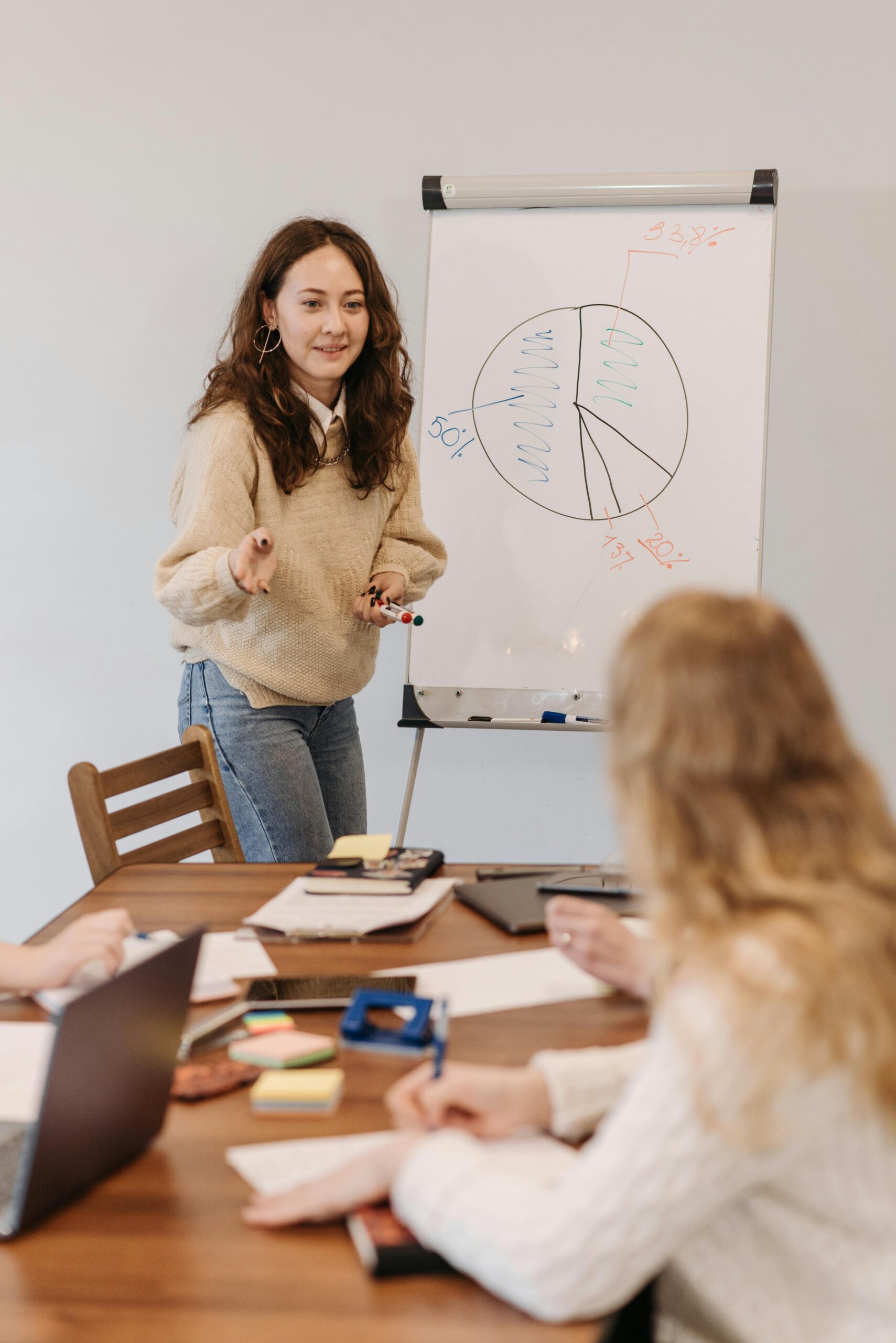Group of adults in a business meeting discussing strategies on a whiteboard.